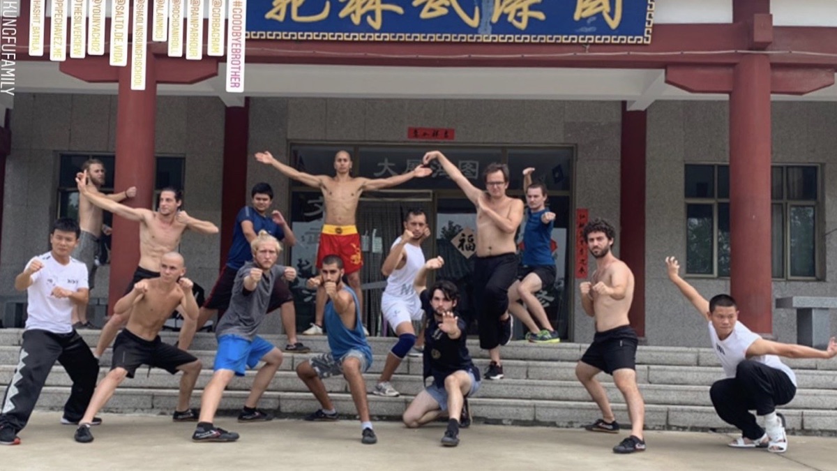 Group photo with training partners outside a kung fu school, everyone in a fighting stance